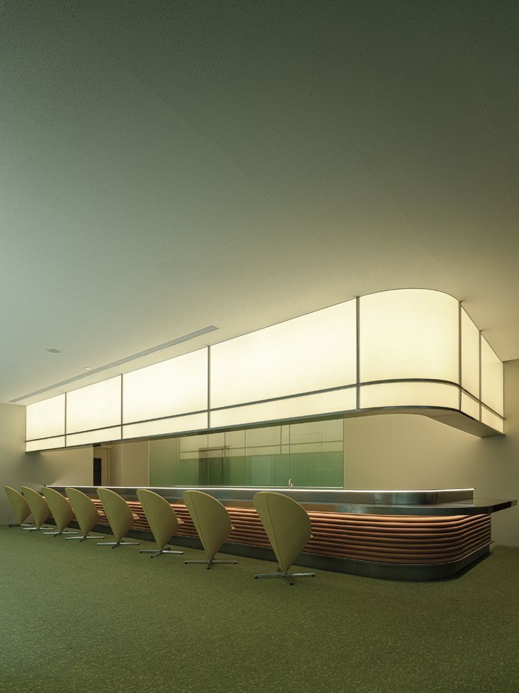 Retro-futurist lounge, cone chairs under a long glowing soffit