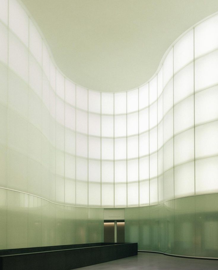 Curved wall of backlit glass panels in an empty lobby